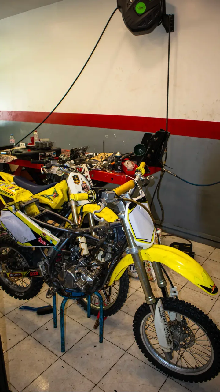 Motos jaunes, dont une partiellement démontée sur un support, dans l’atelier.