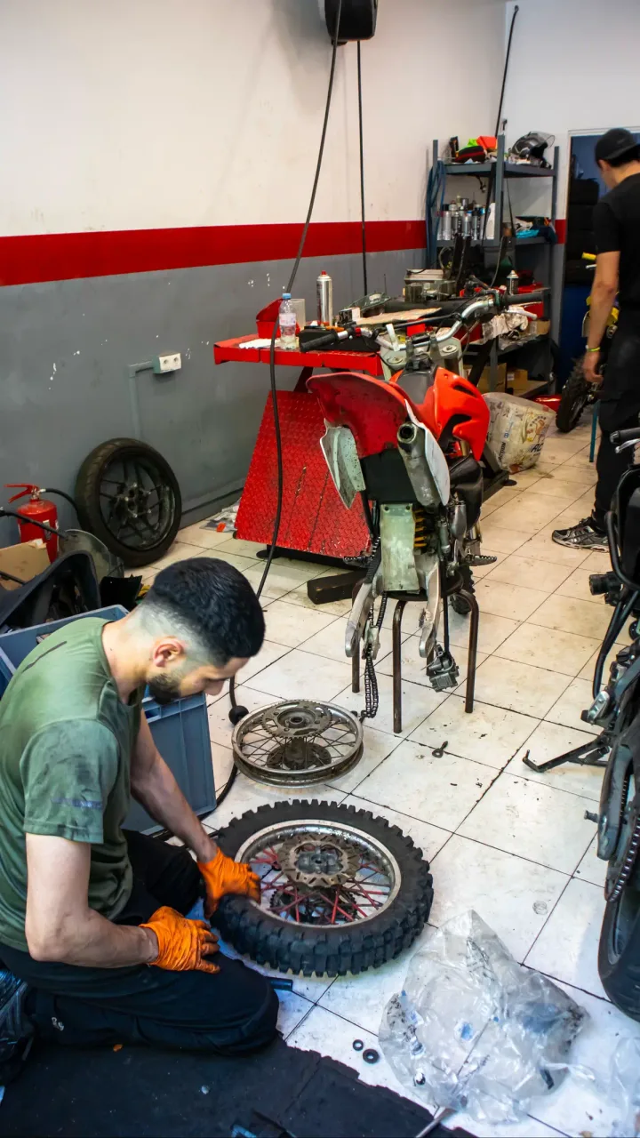 Un mécanicien ganté travaille sur une roue déposée dans l’atelier.
